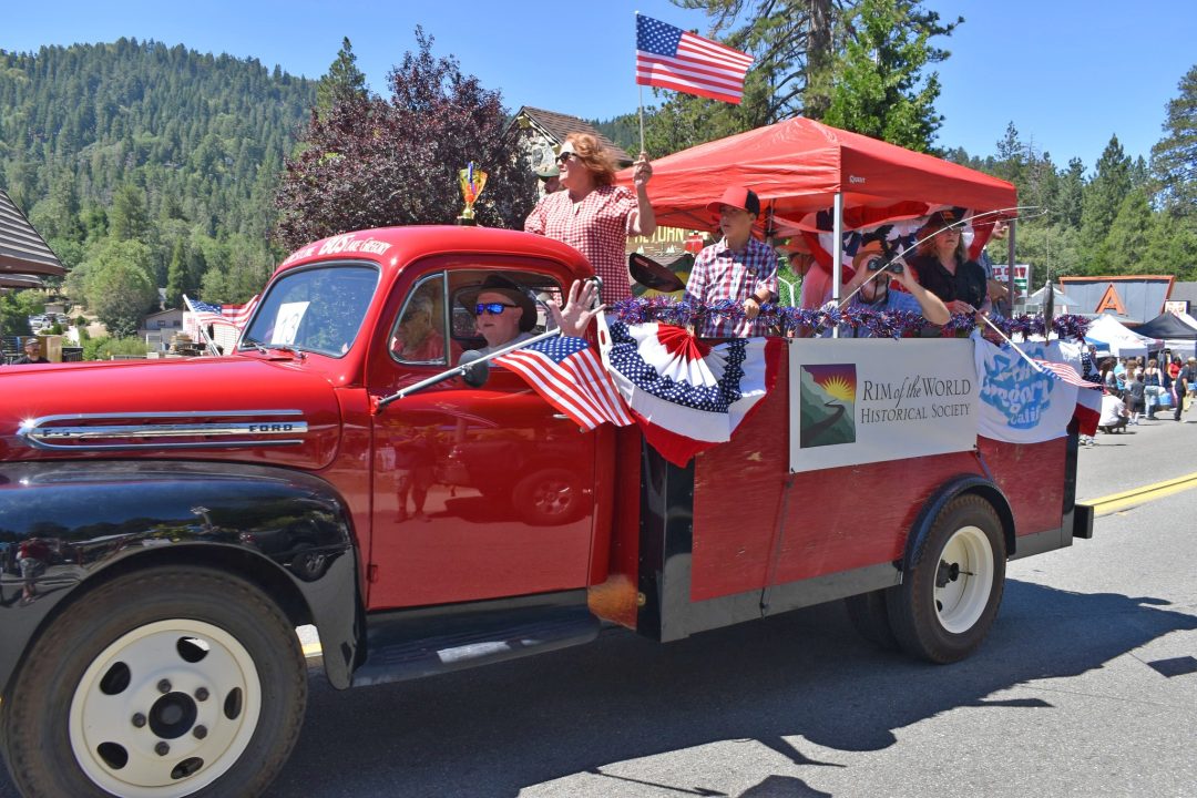 Red parade truck with American flags and people.