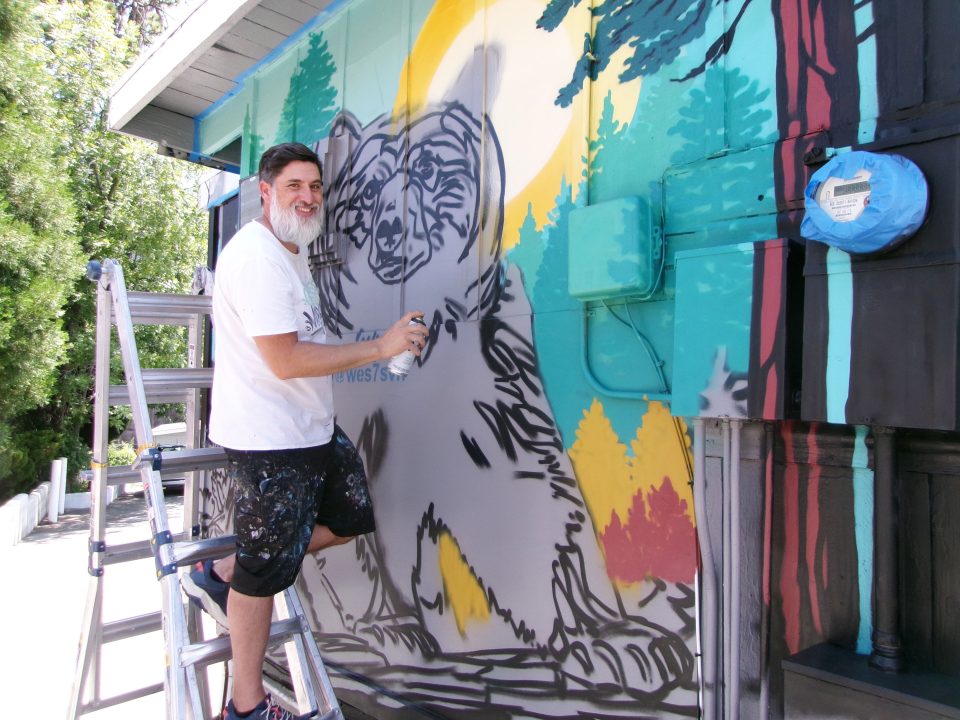 Artist painting colorful bear mural on wall