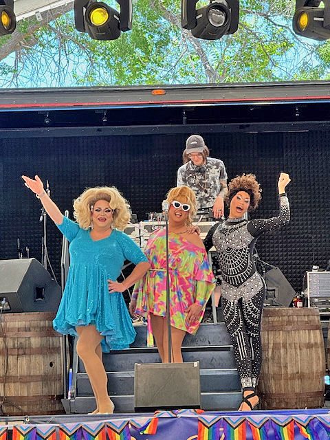 Drag performers on stage with DJ.