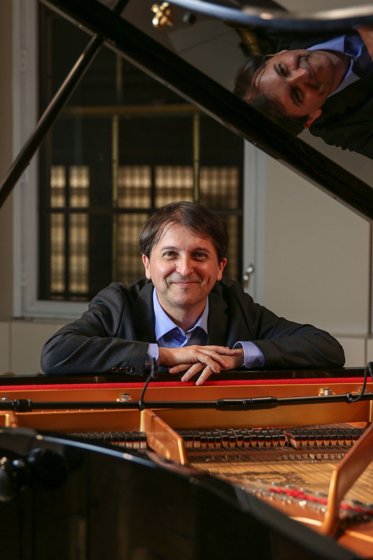 Smiling man at a grand piano.