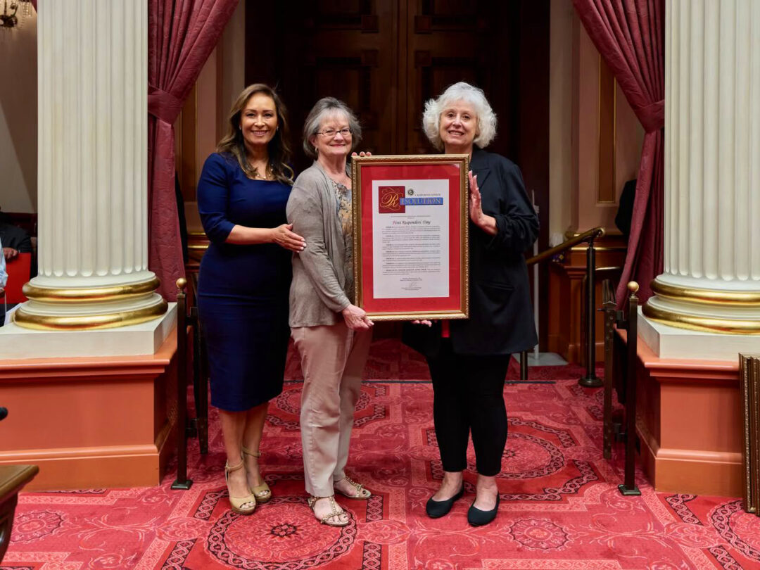 Three women holding a framed resolution indoors.