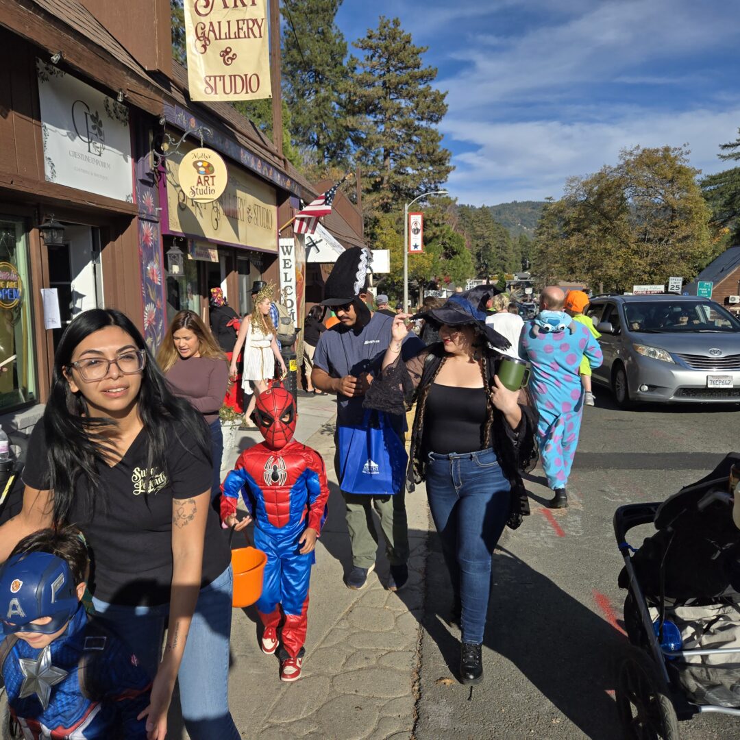 People in Halloween costumes walking on a sunny street.