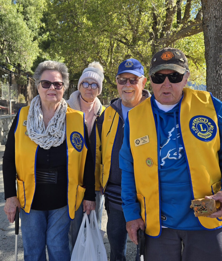 Four people in yellow Lions Club vests outdoors.