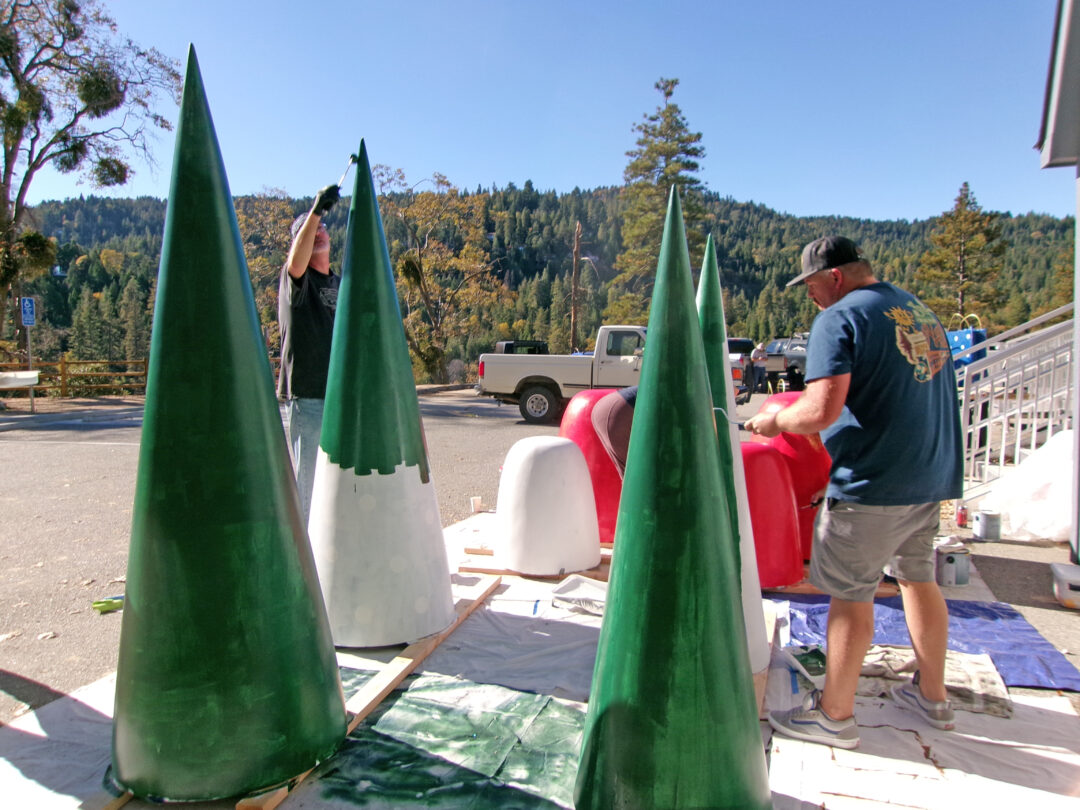 People painting large cone shapes outdoors.