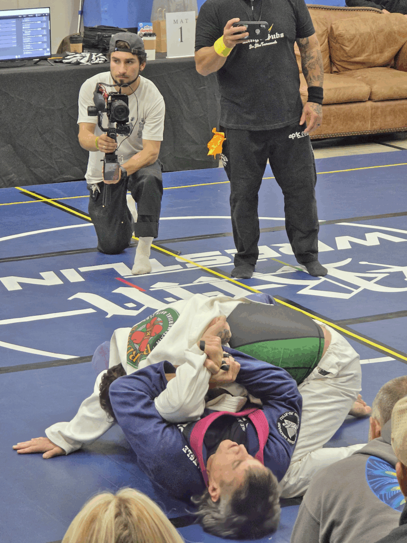 Jiu-jitsu match with photographers and coaches watching.