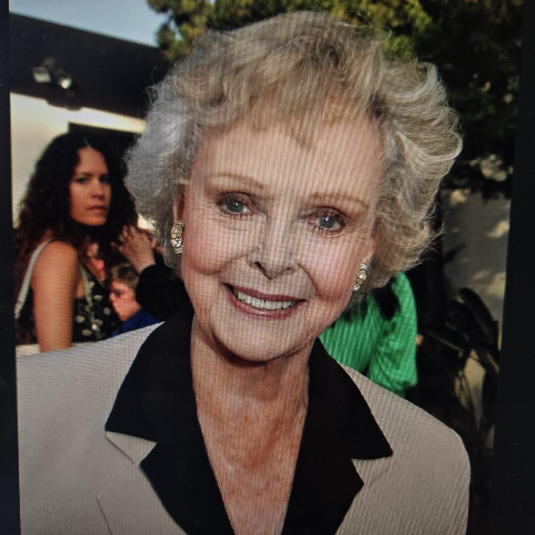 Smiling elderly woman in outdoor setting.