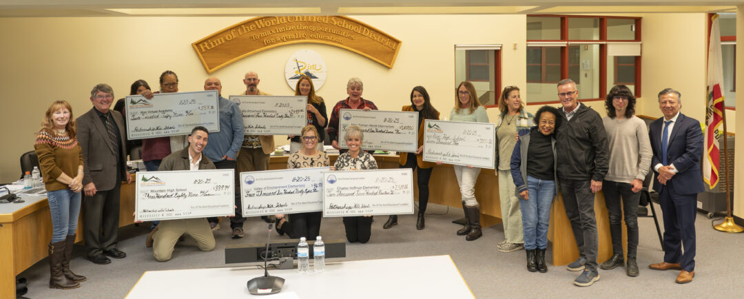 Group holding oversized checks in a meeting room.