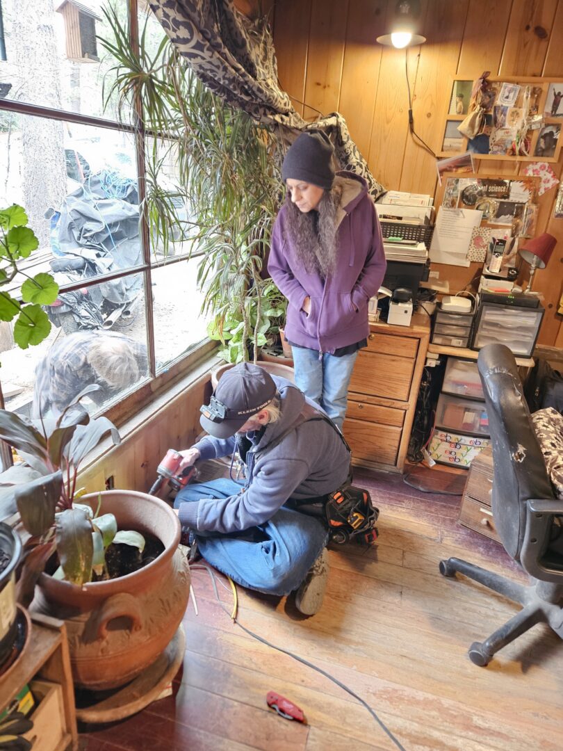 Homeowner Judith watches as Jesse McDougall from Shafe Electric replaces an electrical outlet. (Photo by Mary-Justine Lanyon)