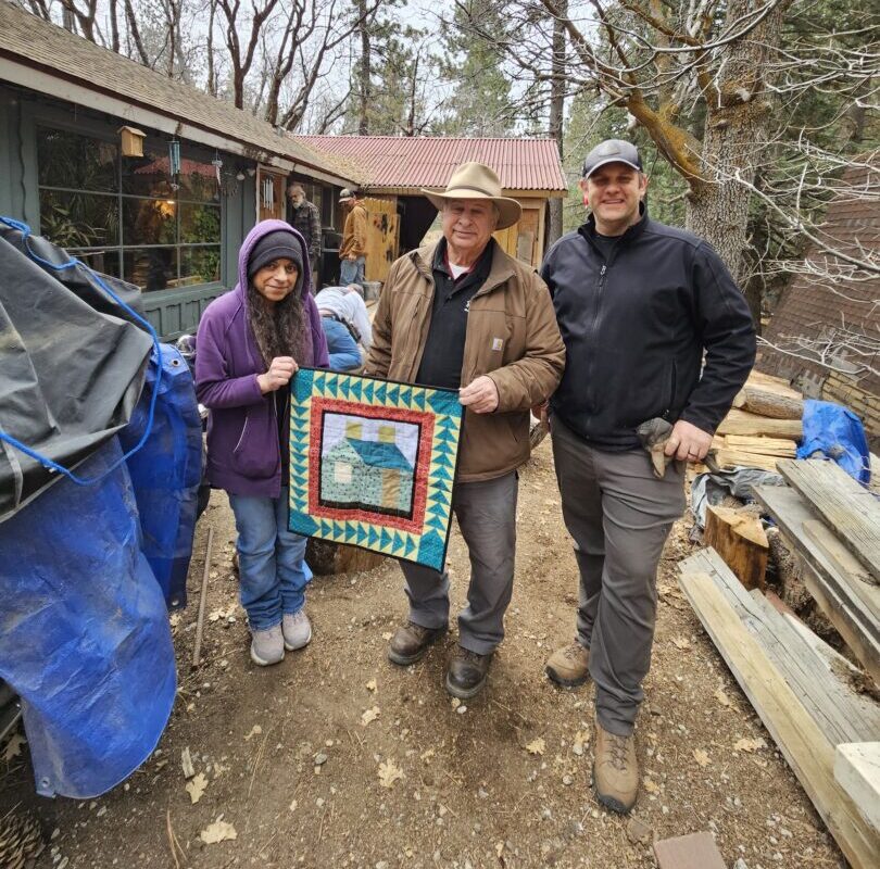 Wayne Palmer (center) and Robert Block presented Green Valley Lake homeowner Judith with a quilted wall hanging from the Dogwood Quilters. (Photo by Mary-Justine Lanyon)